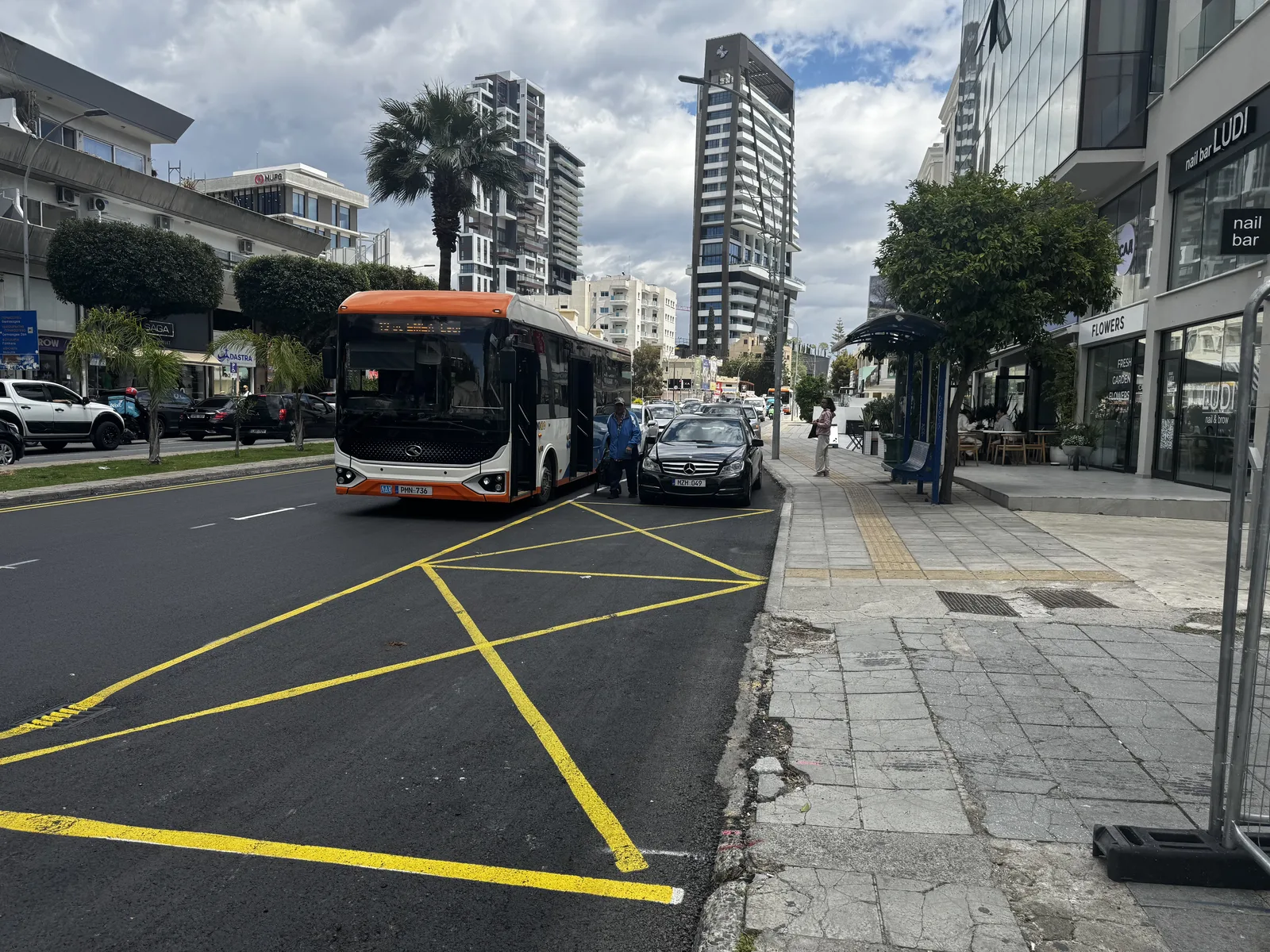 Εσοχή στάσης σε δρόμο της Λεμεσού: ένα αυτοκίνητο είναι σταθμευμένο μέσα στην εσοχή και το λεωφορείο έχει σταματήσει έξω, στη λωρίδα κυκλοφορίας